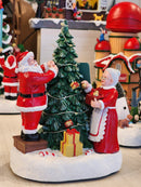 CENÁRIO VILA NATALINA PAPAI E MAMÃE NOEL MONTANDO A ÁRVORE 28CM  - PRÉ VENDA 2025